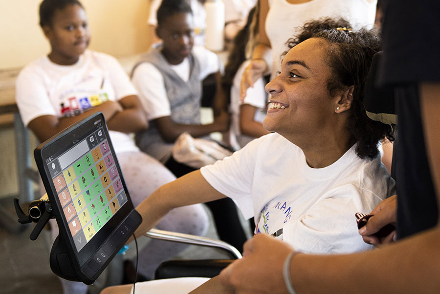 Young woman with cerebral palsy using TD Snap AAC app on a speech generating device