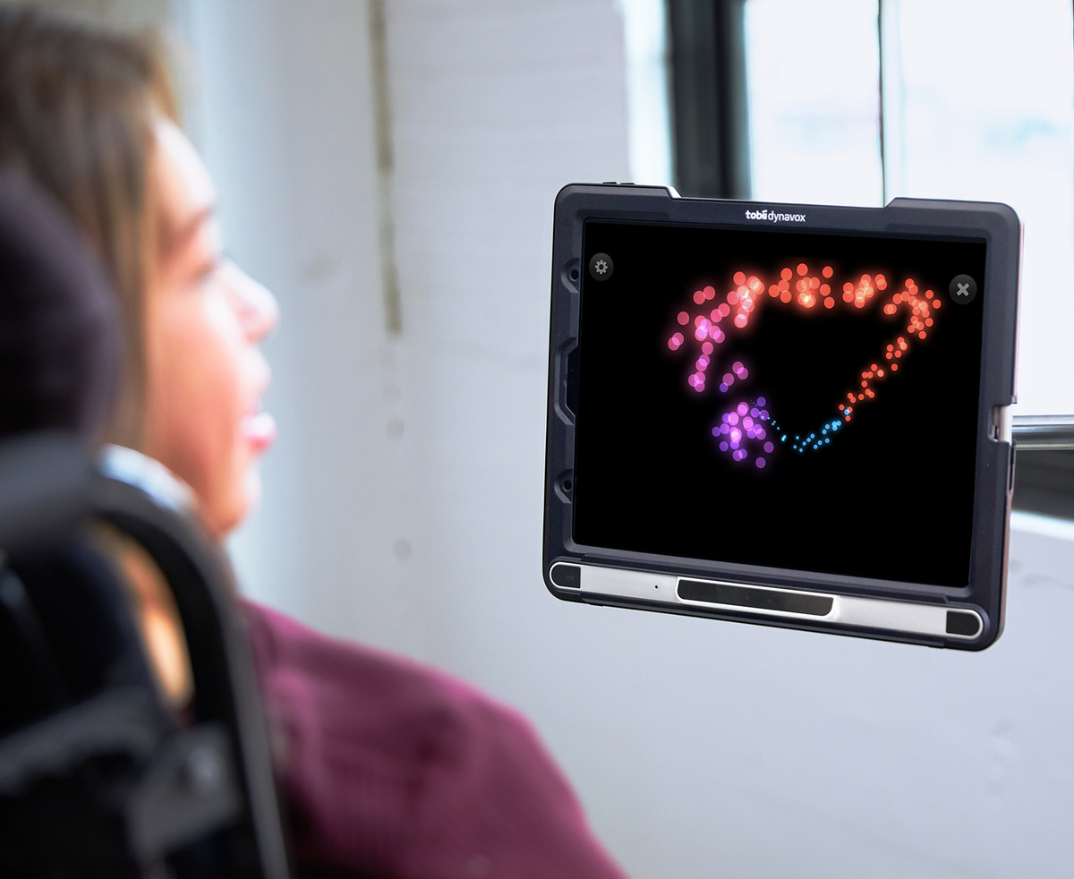  A young woman with cerebral palsy using the Sensory Eye FX 2 colorful graphic activities on her TD Pilot eye gaze speech device